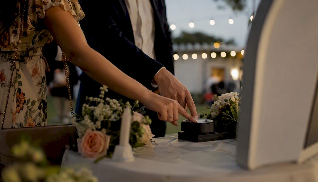 Guests pressing a photo booth activation button at a reception
