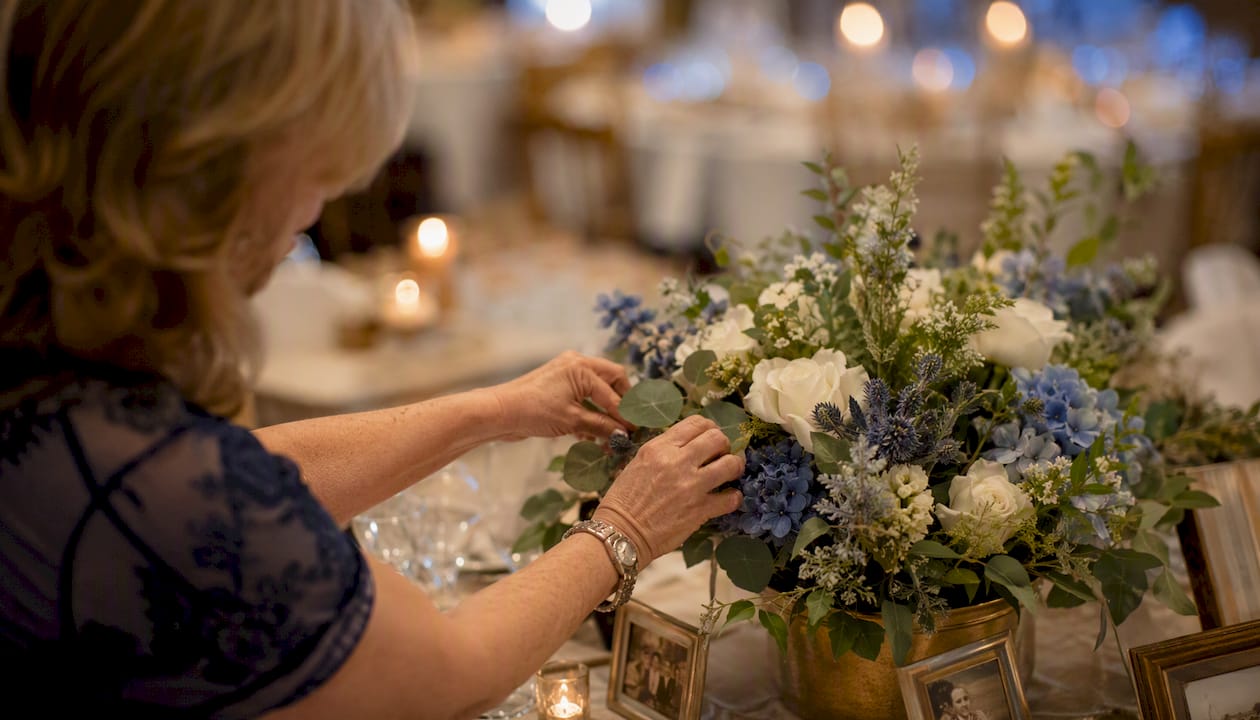 Hands arranging centerpiece in warmly lit wedding reception