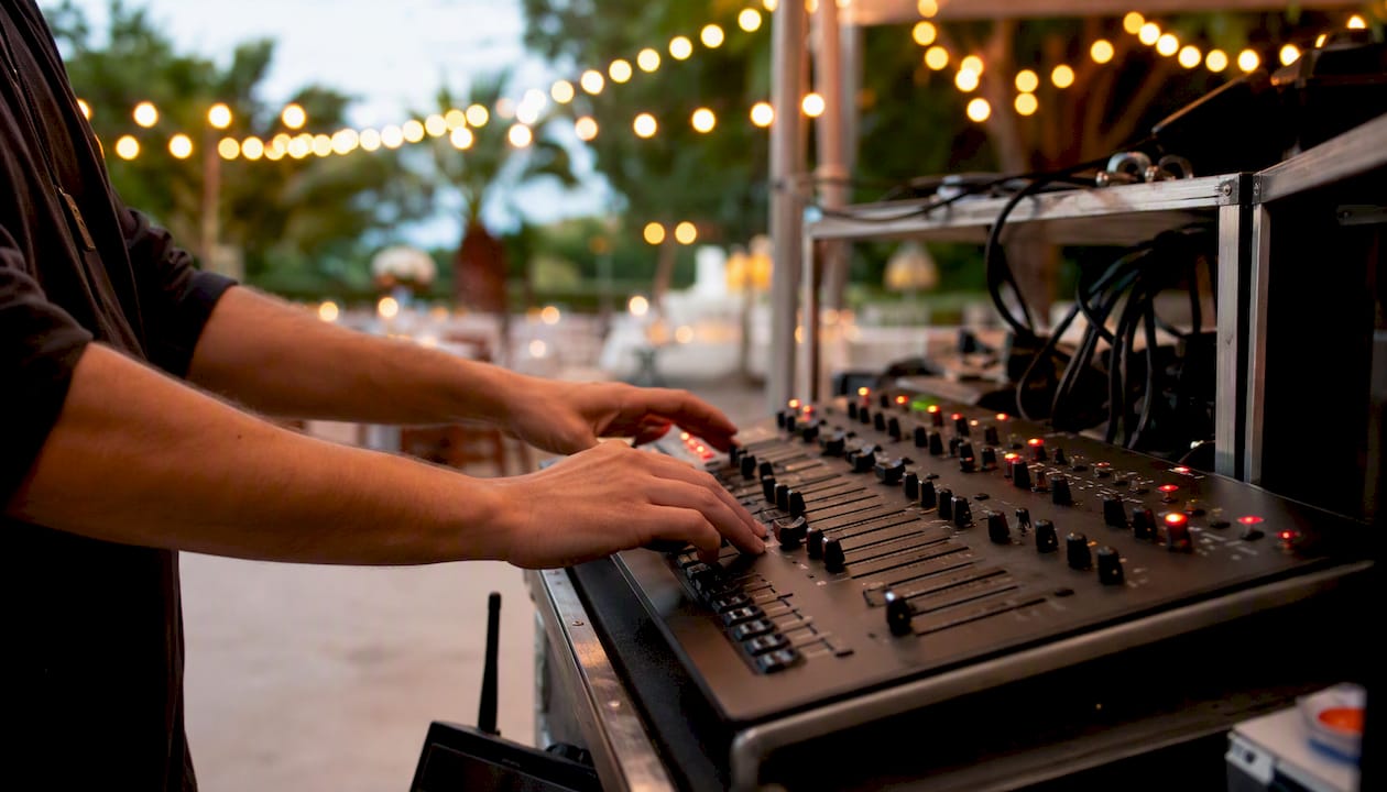 Hands adjusting event lighting controls backstage
